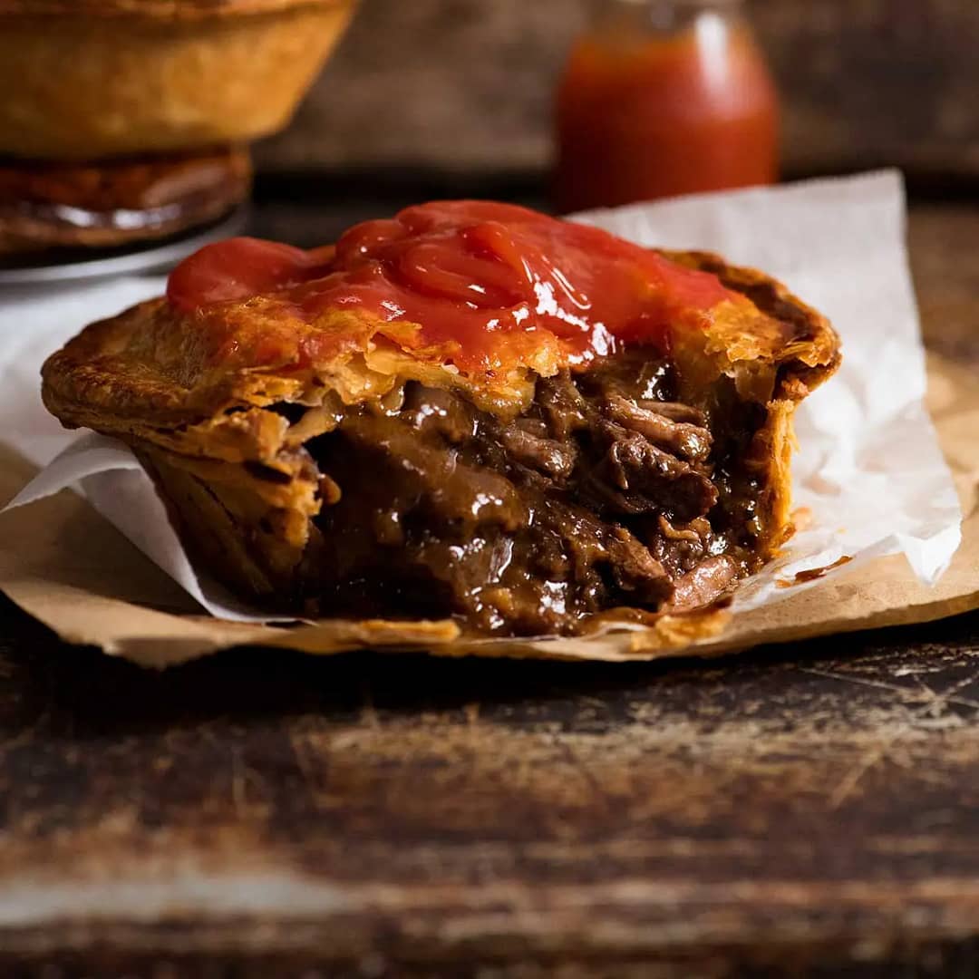 A freshly baked Aussie meat pie with rich, savory filling.
