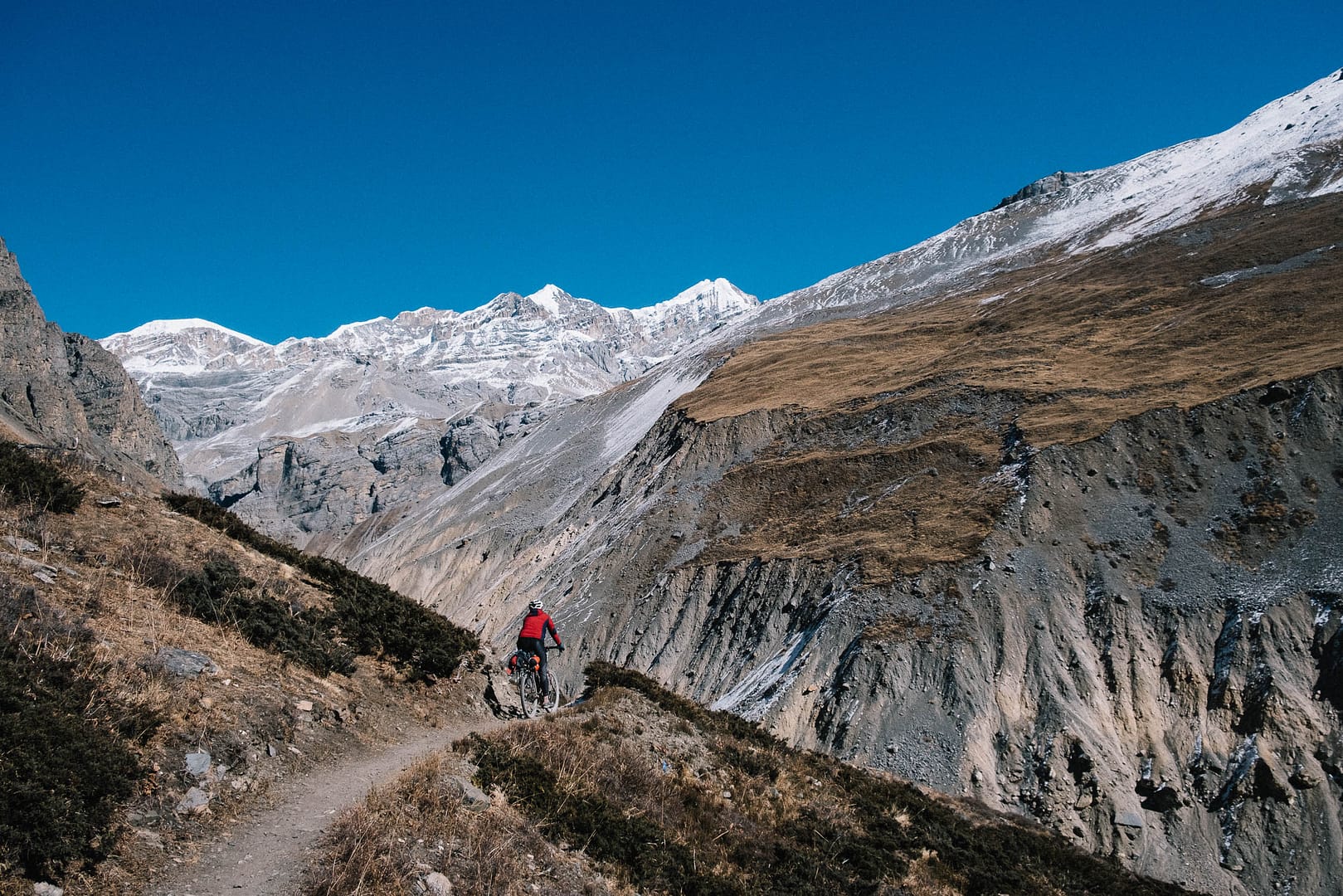 Trekkers crossing the Thorong La Pass with snowy peaks in the background. 