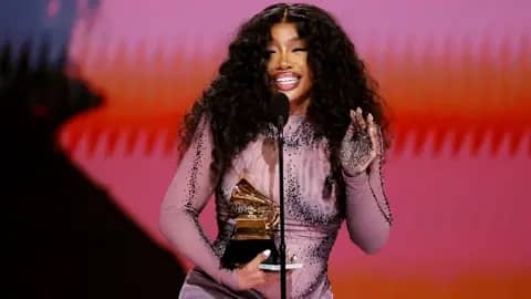 Grammys 2024 stage with dazzling lights and musicians performing.