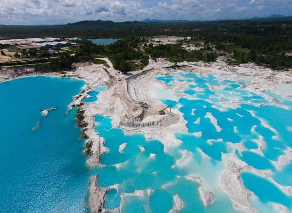 Pemandangan menakjubkan Danau Kaolin dengan air biru kehijauan yang kontras dengan tanah putih di sekitarnya, menciptakan lanskap yang unik dan indah