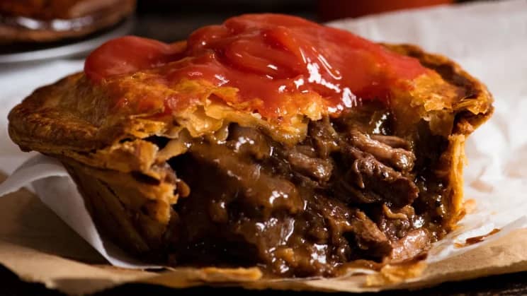 A delicious homemade meat pie sliced open to reveal its savory filling of meat and vegetables.