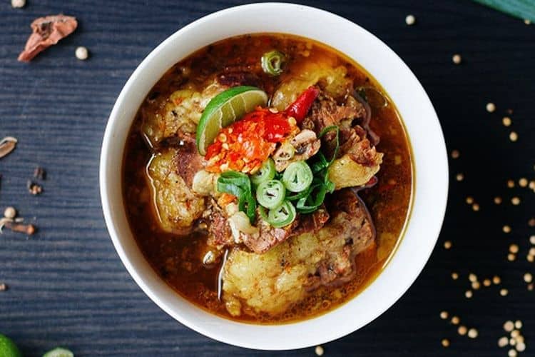 Sup Konro Khas Makassar - Semangkuk Sup Konro dengan iga sapi empuk yang disajikan dengan kuah kaya rempah, lengkap dengan taburan bawang goreng dan perasan jeruk nipis