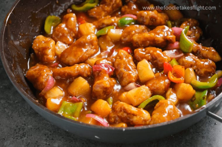 A plate of Sweet and Sour Pork with vibrant bell peppers and pineapple chunks 